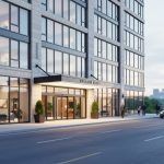 Modern hotel exterior in Saskatoon, Saskatchewan with soft daylight and a blurred view of the river valley in the background.